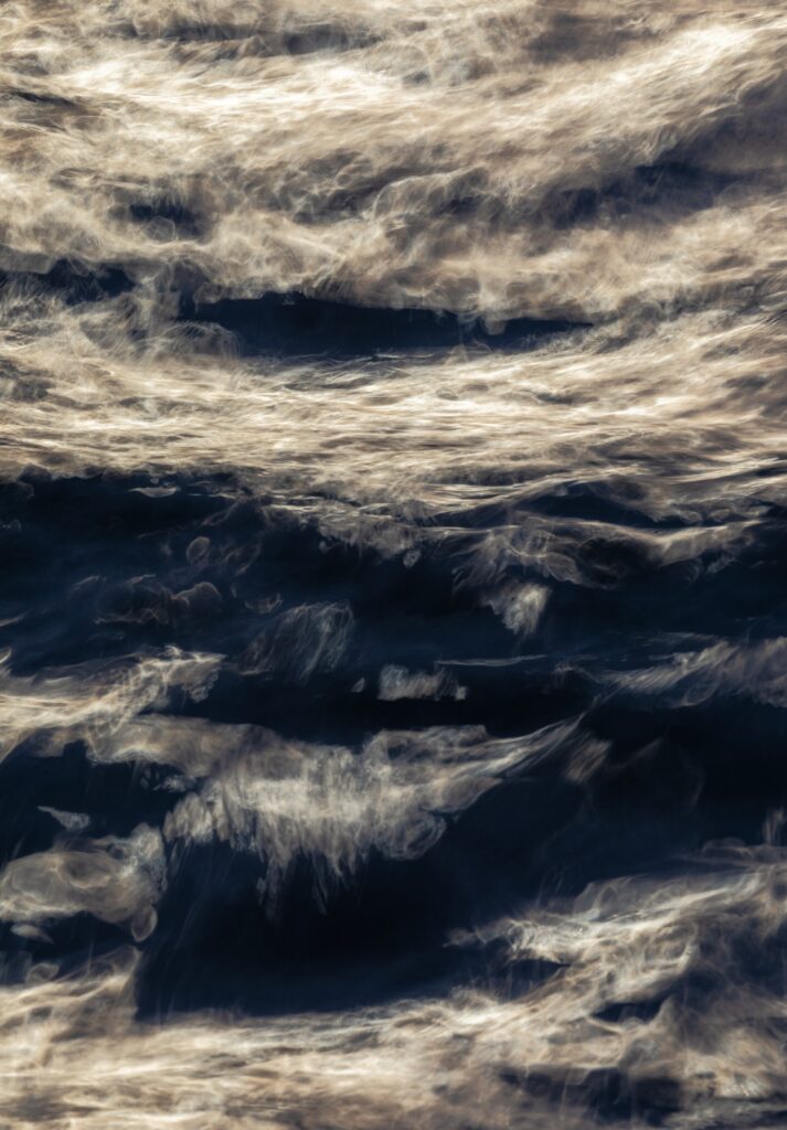 Abstract wallpaper of dynamic foamy sea waves swirling over deep blue ocean with light reflections