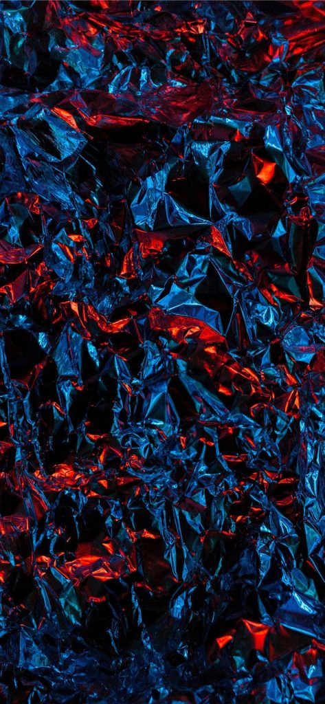 Close-up abstract crumpled metallic foil texture with blue shadows and red highlights wallpaper