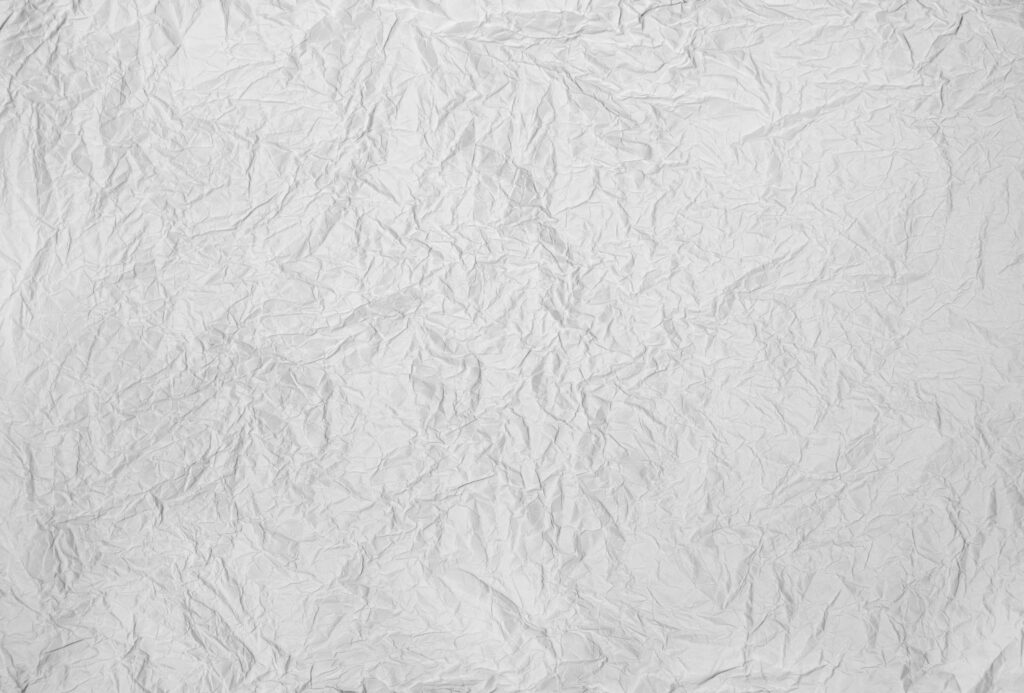 High-resolution crumpled white paper texture with wrinkles shadows and highlights wallpaper background