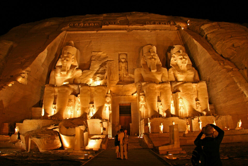 Great Temple of Abu Simbel illuminated at night with monumental statues and sandstone cliffs Wallpaper