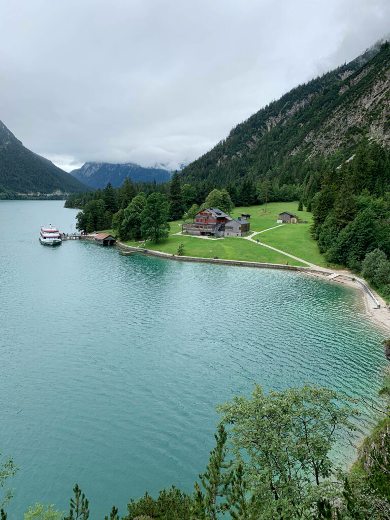Achen Lake Austria serene lakeside cabin lush hills alpine mountains cloudy sky wallpaper