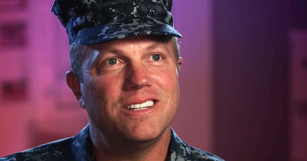 Adam Baldwin in camouflage military uniform with confident friendly expression blurred background Wallpaper