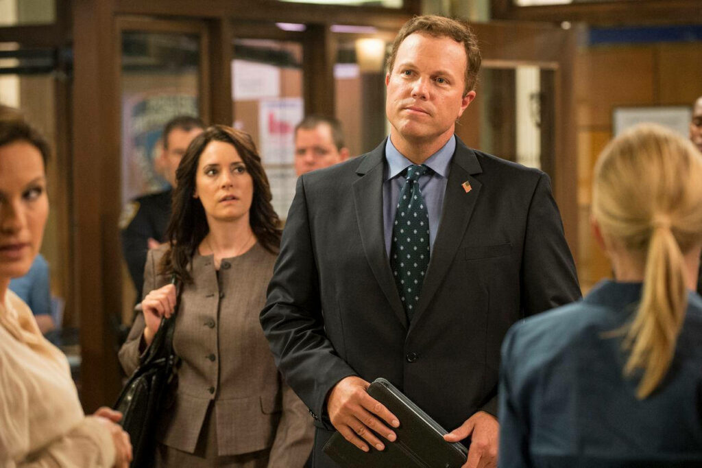 Adam Baldwin as Steven Harris in suit leads serious office discussion with colleagues background Wallpaper