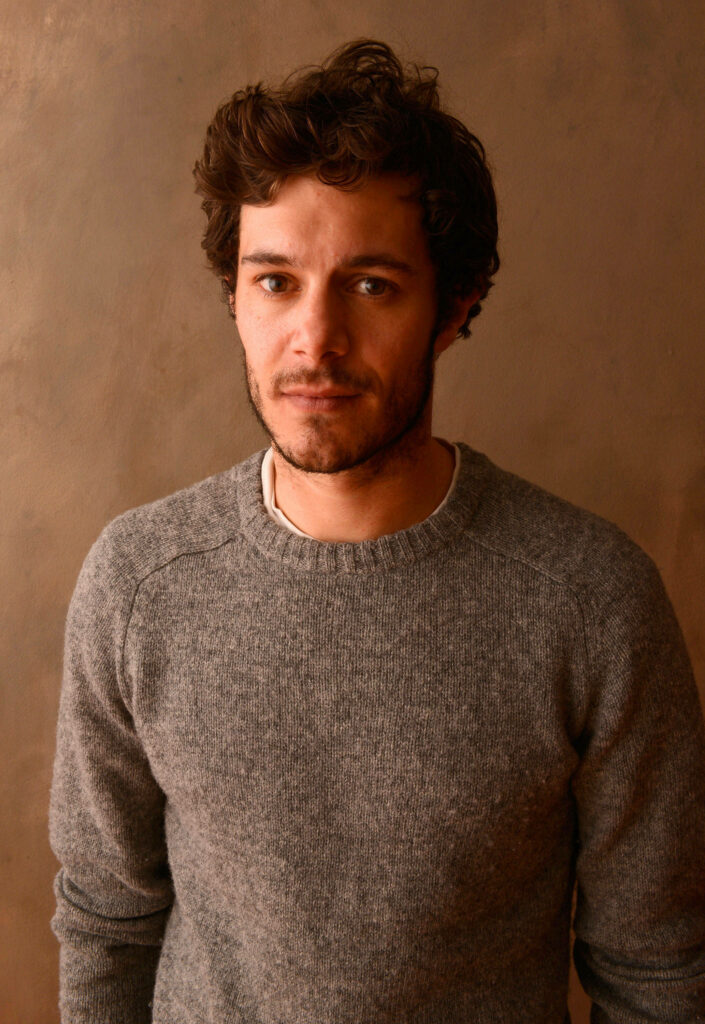 Adam Brody in cozy gray sweater posing against warm brown background simple natural portrait Wallpaper