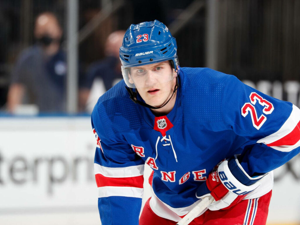 Adam Fox in blue New York Rangers uniform focused on ice hockey dynamic wallpaper background