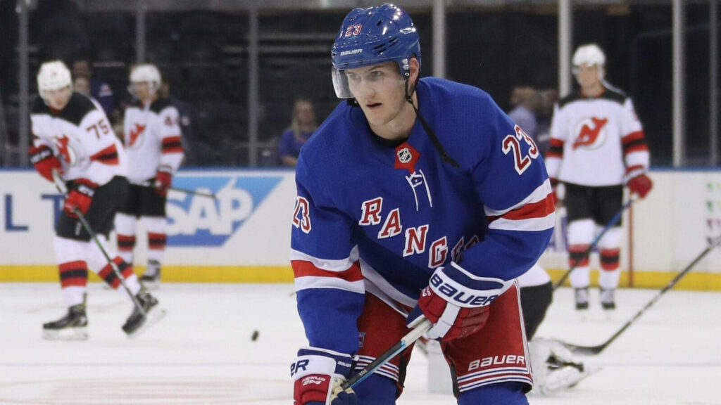Adam Fox New York Rangers focused on ice in blue jersey preparing against New Jersey Devils Wallpaper