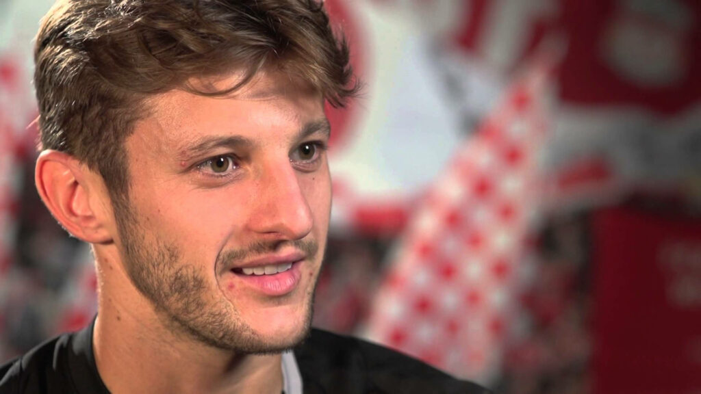 Adam Lallana close-up with shy smile relaxed friendly expression blurred wallpaper background