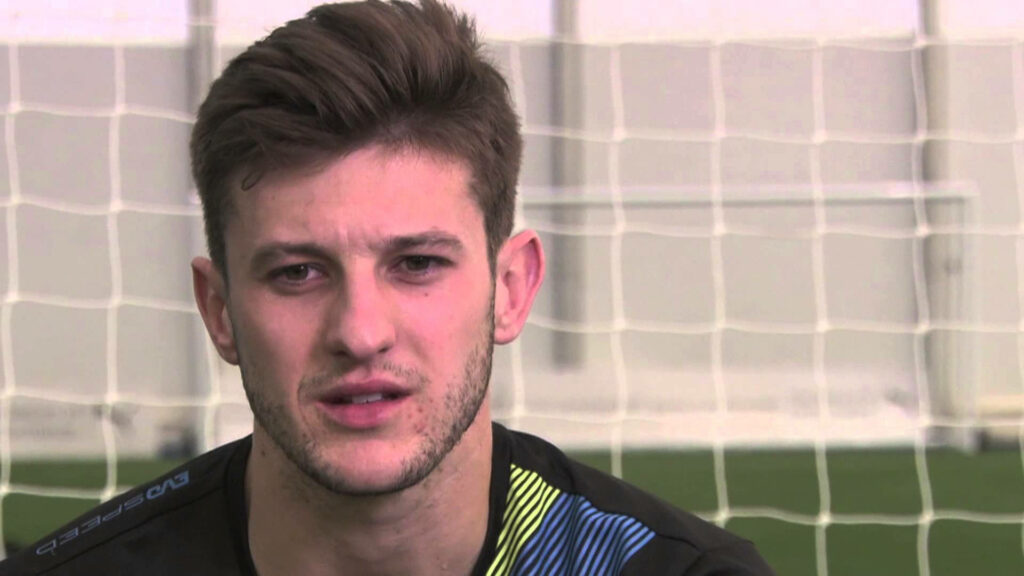 Adam Lallana focused football player in front of goal net wallpaper background close up
