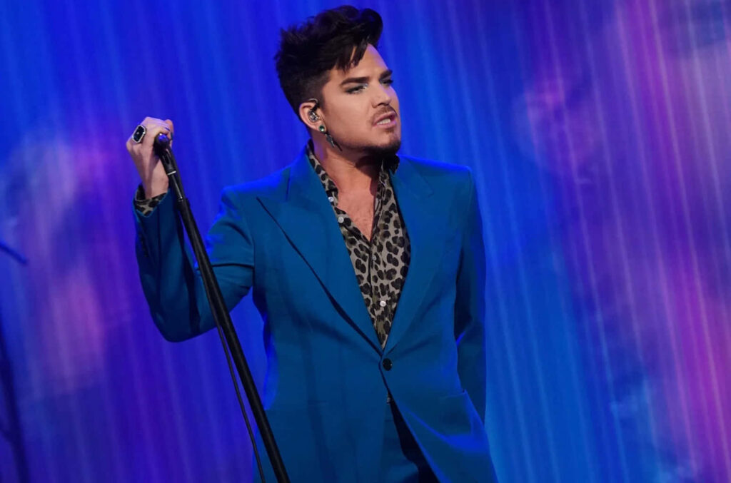 Adam Lambert performing live in vibrant blue suit and leopard print shirt on blue-lit stage Wallpaper