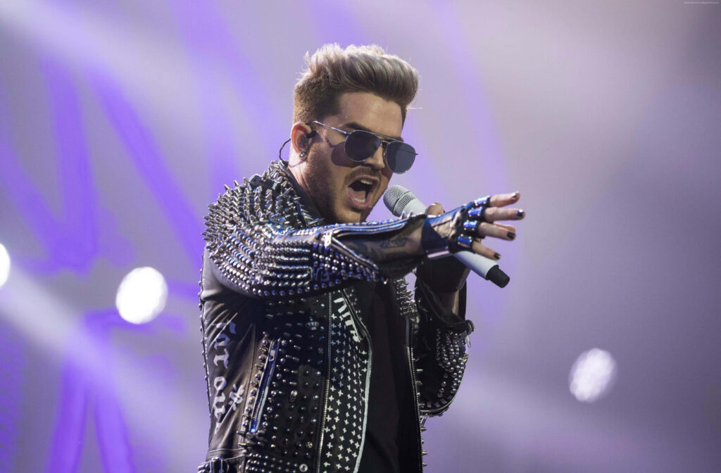 Adam Lambert performing live in studded outfit and sunglasses dramatic lighting concert wallpaper