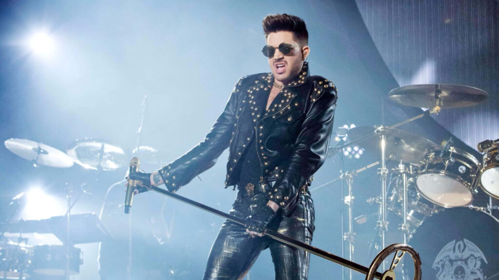 Adam Lambert singing passionately on stage in leather outfit with dynamic concert background Wallpaper