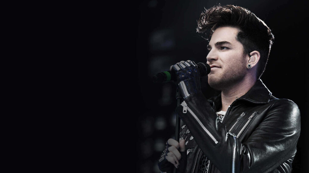 Adam Lambert performing on stage in black leather jacket and gloves holding microphone close-up Wallpaper