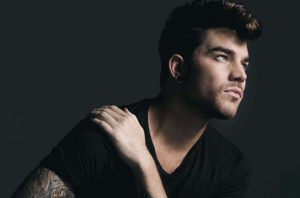 Adam Lambert wallpaper thoughtful pose dark background expressive gaze stylish appearance