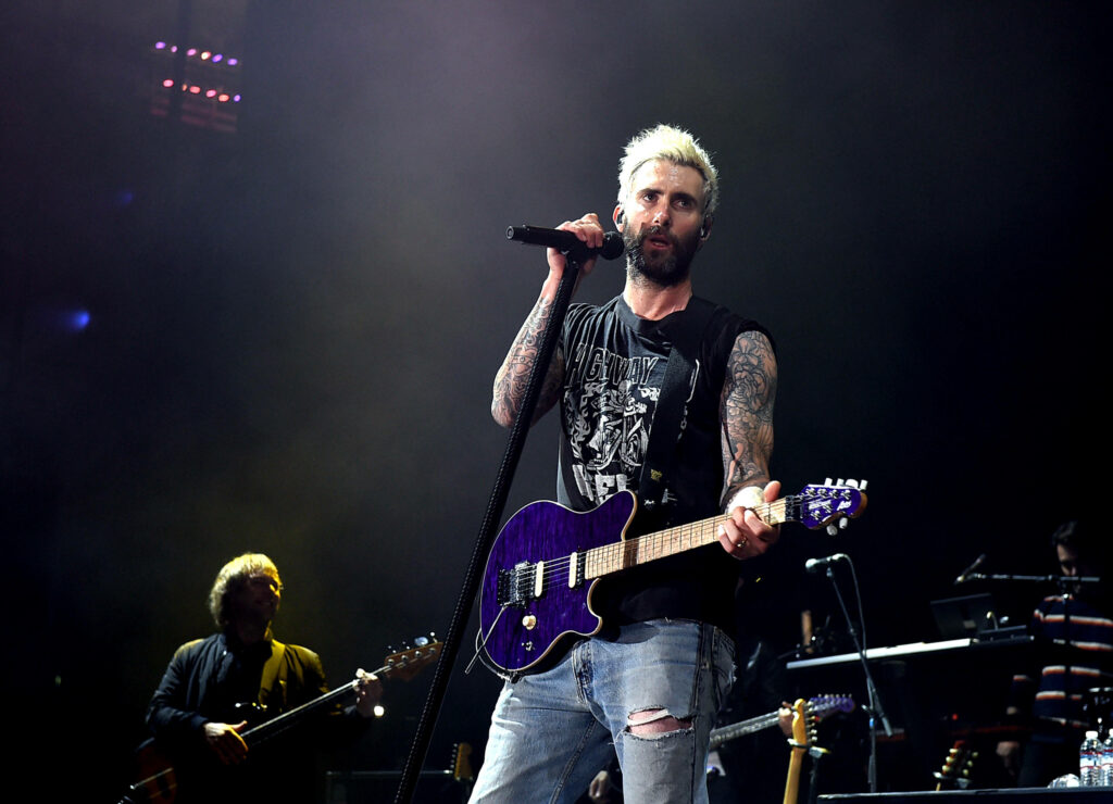 Adam Levine rocking stage with purple guitar, vibrant lighting, and dynamic band performance. Wallpaper