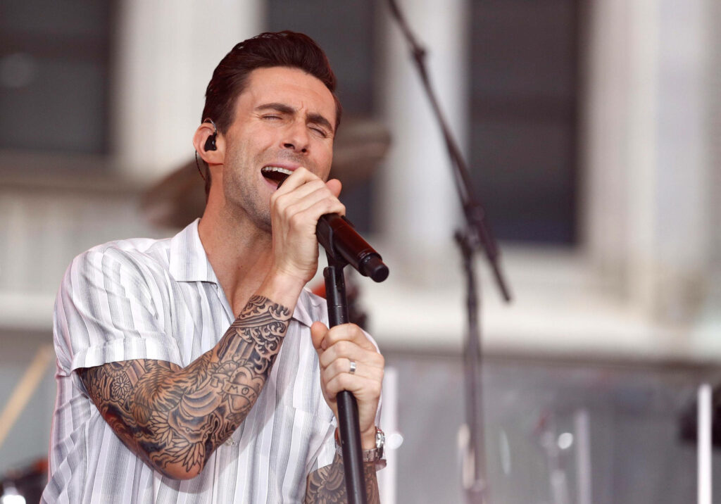 Adam Levine performing passionately on stage with vibrant energy and signature tattoos wallpaper