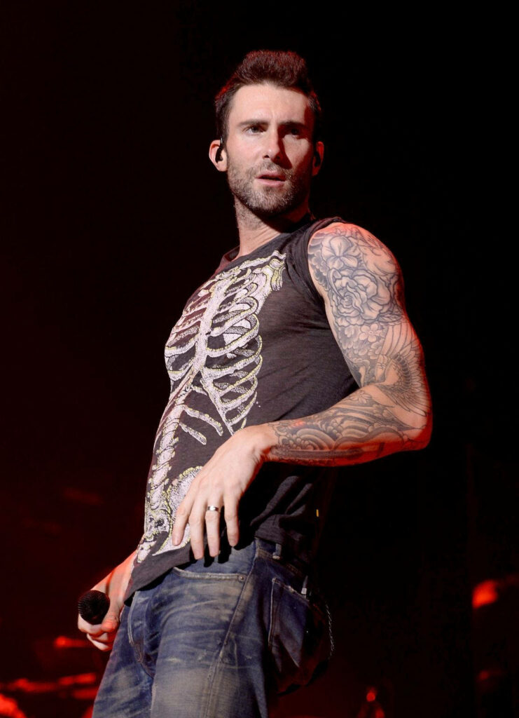Adam Levine live performance in skeleton tee, showcasing tattooed arms, vibrant wallpaper design.
