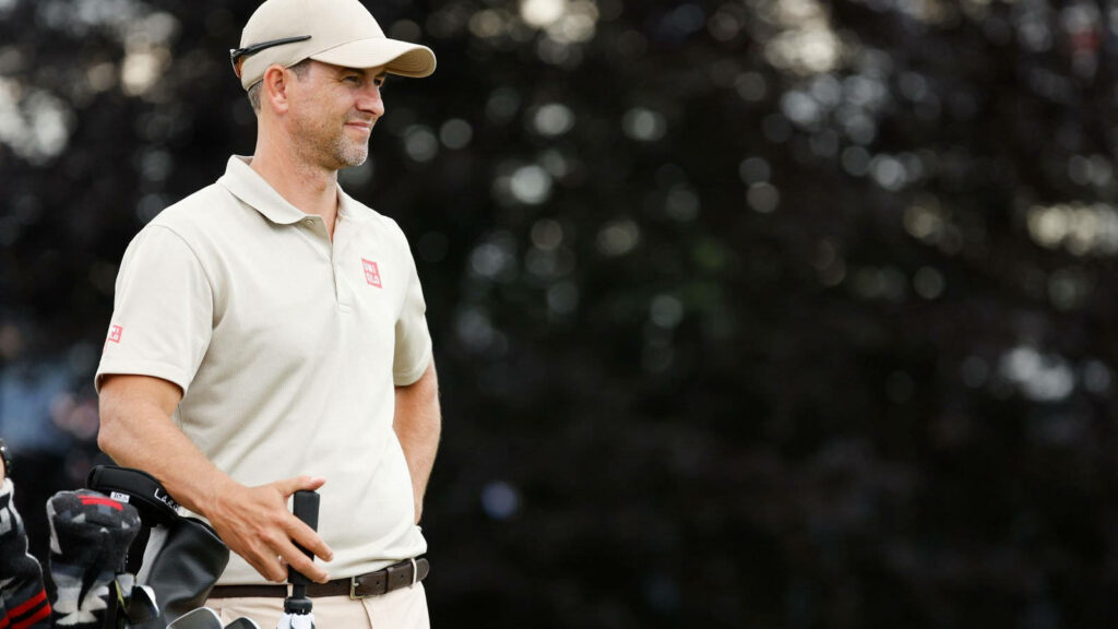 Adam Scott on golf course in beige collared shirt and cap with golf clubs and relaxed look Wallpaper