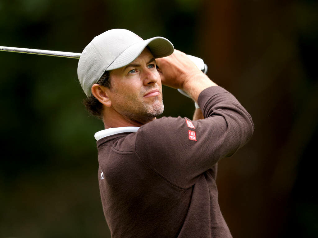 Adam Scott focused golf swing brown sweater light cap natural blurred background wallpaper