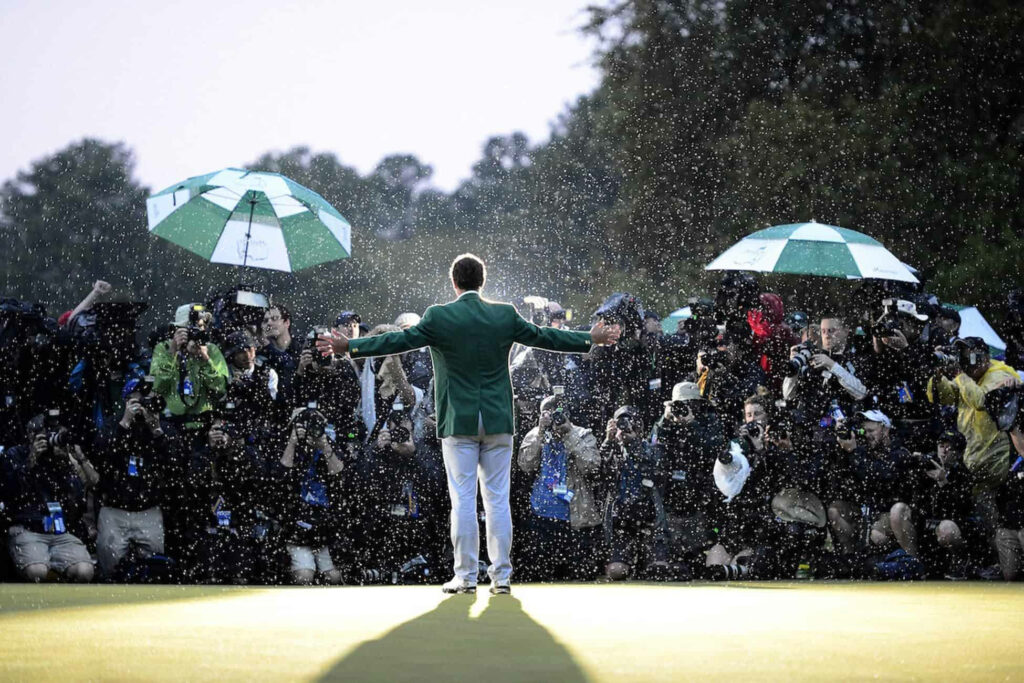 Adam Scott in green jacket celebrates on golf course with arms outstretched in rain crowds Wallpaper