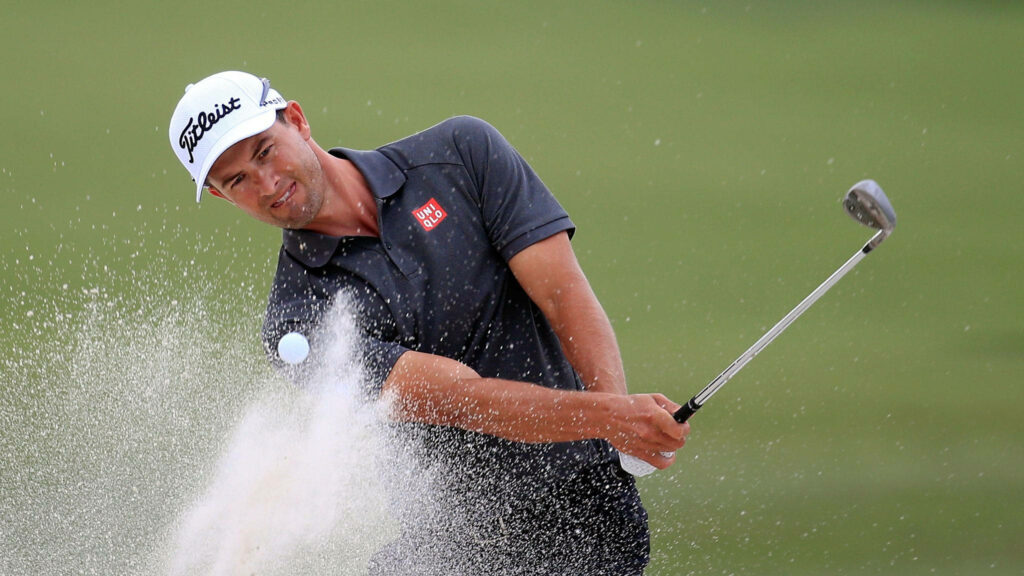 Adam Scott hitting golf ball from sand bunker with focus during intense golf match wallpaper