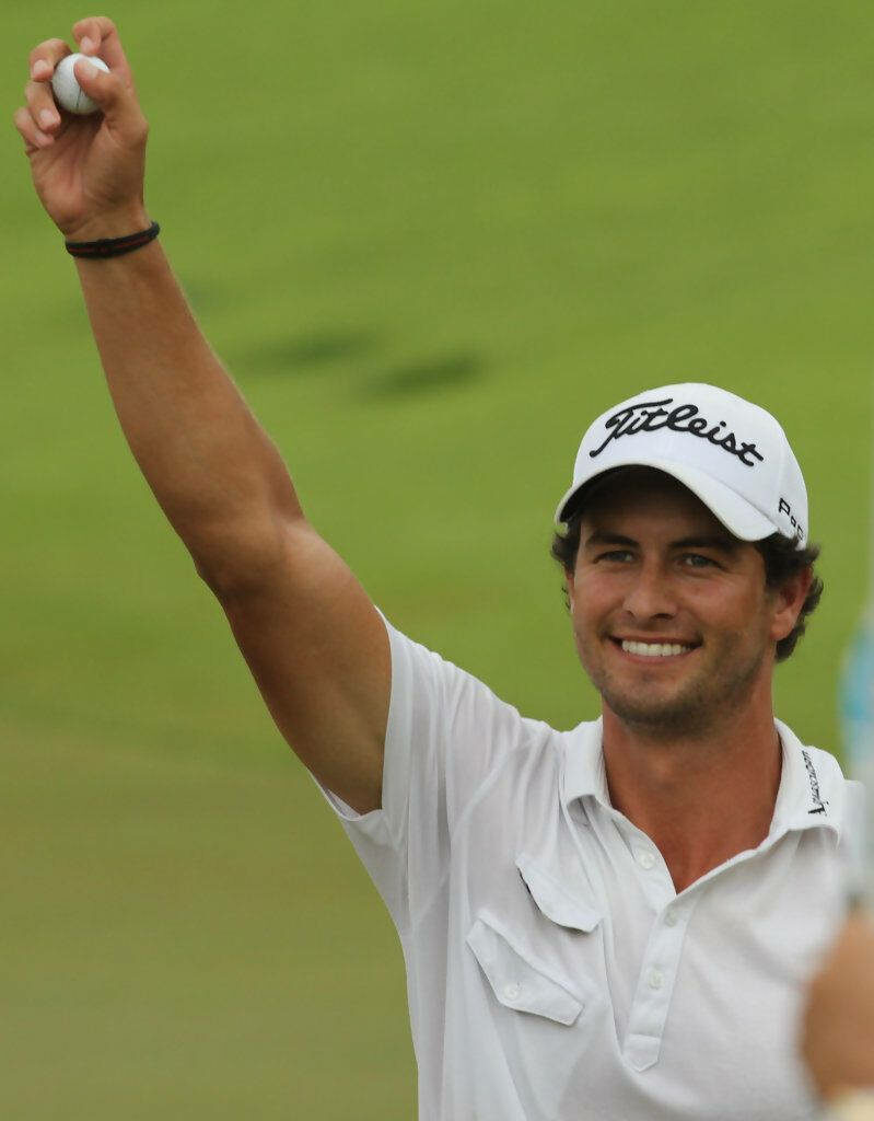 Adam Scott celebrating golf victory holding winning golf ball smiling on green background Wallpaper