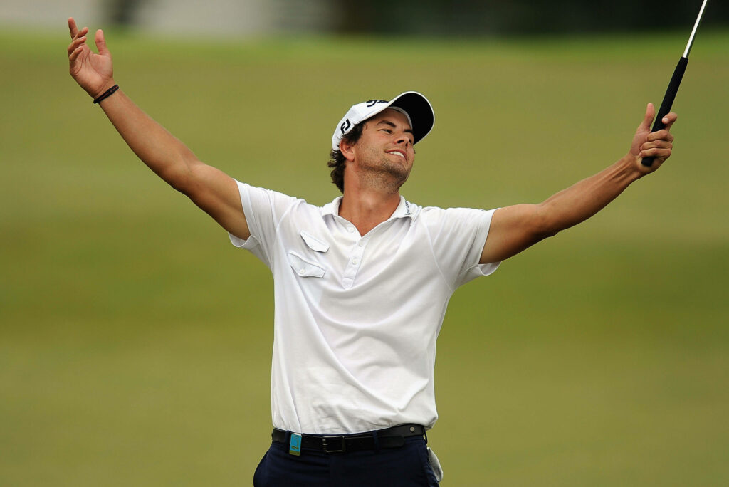 Adam Scott victorious celebrating on golf course with arms raised lush green wallpaper background