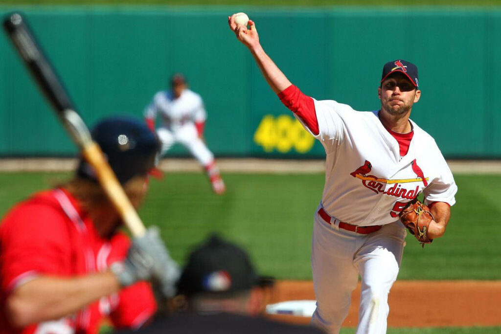 Adam Wainwright pitching a baseball in action during an intense game with green outfield background Wallpaper