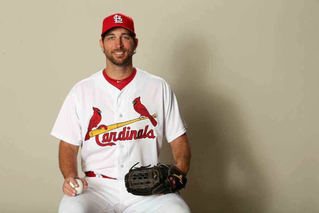Adam Wainwright smiling in St Louis Cardinals uniform holding baseball and glove isolated background Wallpaper