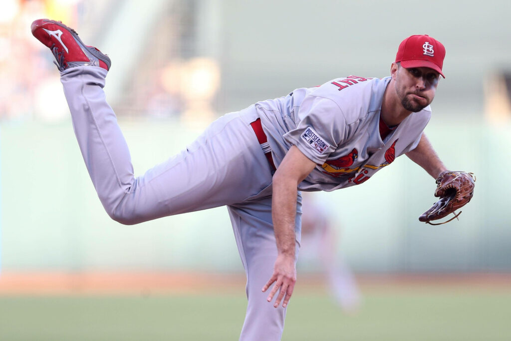 Adam Wainwright pitching with raised leg in St Louis Cardinals uniform on baseball field wallpaper