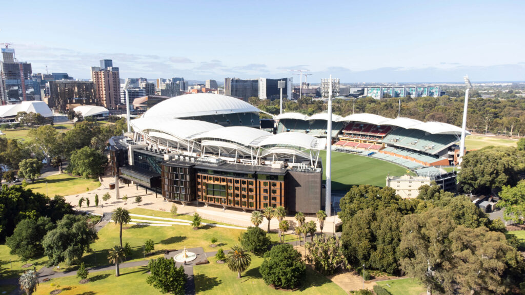 Aerial view of Adelaide Oval stadium with iconic architecture lush greenery and city skyline Wallpaper