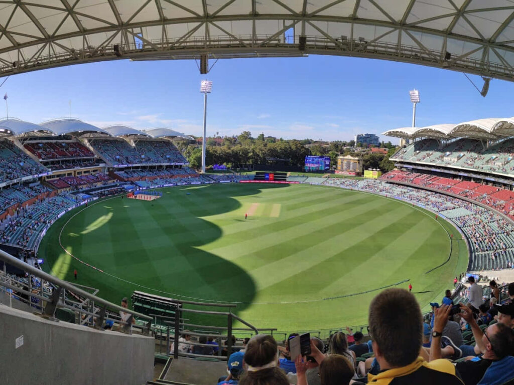 Adelaide Oval cricket match vibrant green field packed stands clear blue sky wallpaper background