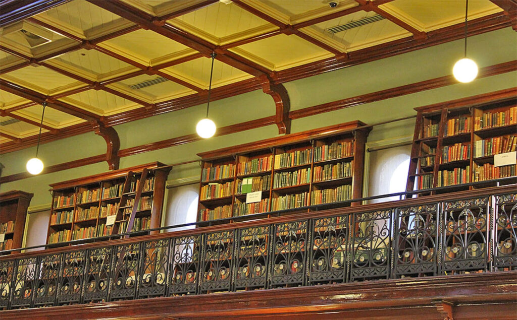 Adelaide State Library interior balcony with classic bookshelves ornate railings and warm lighting wallpaper