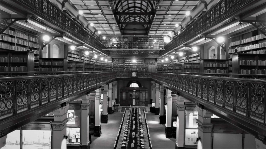 Black and white wallpaper of Adelaide State Library interior with ornate ironwork and tall bookshelves
