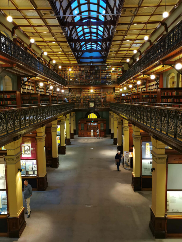 Adelaide State Library interior with iron railings wooden bookshelves and glass ceiling light Wallpaper