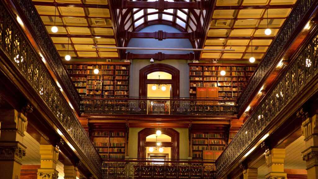 Adelaide State Library interior with elegant iron balconies warm wooden bookshelves classic design Wallpaper
