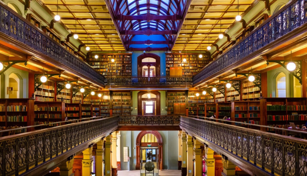 Adelaide State Library interior with grand arches ornate railings bookshelves and glass ceiling Wallpaper