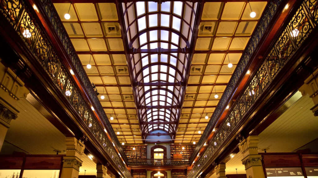 Interior of Adelaide State Library with vaulted ceiling ironwork balconies and cozy reading areas Wallpaper