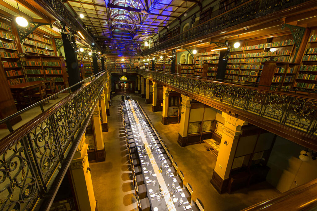 Adelaide State Library interior with tall bookshelves ornate iron railings and glass ceiling wallpaper