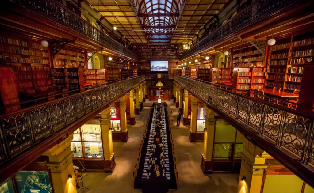 Grand interior of Adelaide State Library with ornate architecture and glowing bookshelves wallpaper