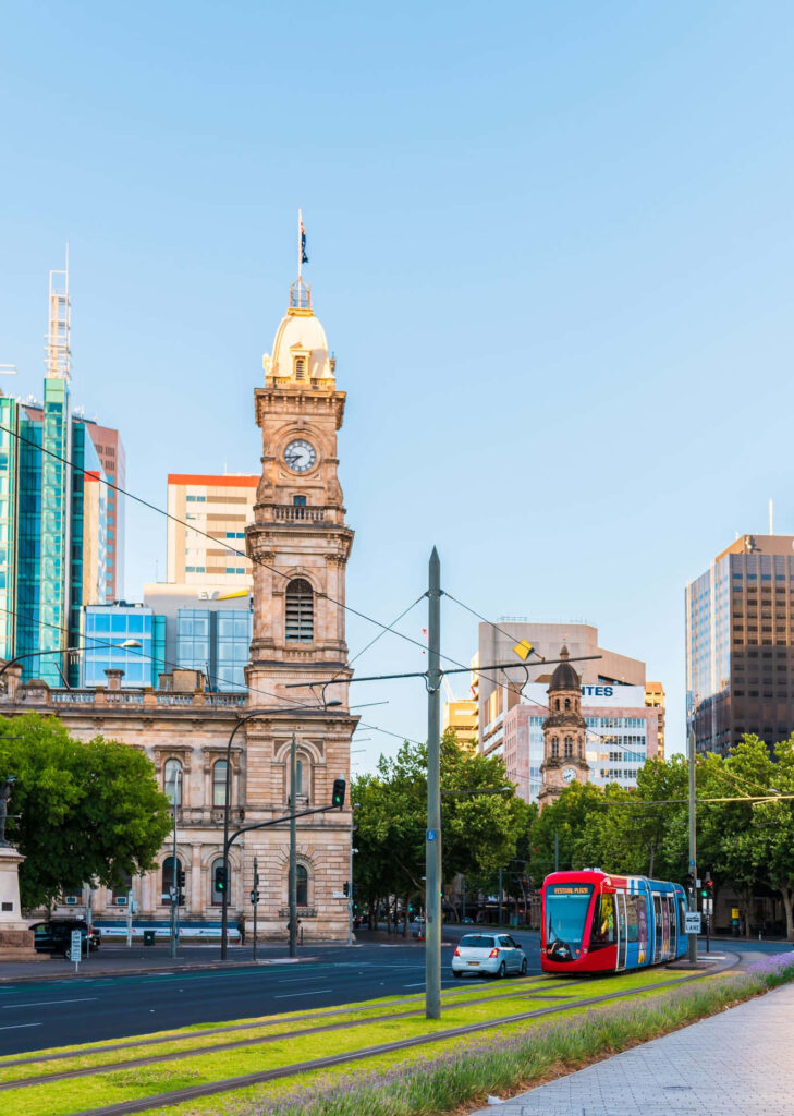 Adelaide Victoria Square Clock Tower with modern cityscape and colorful tram on clear day Wallpaper