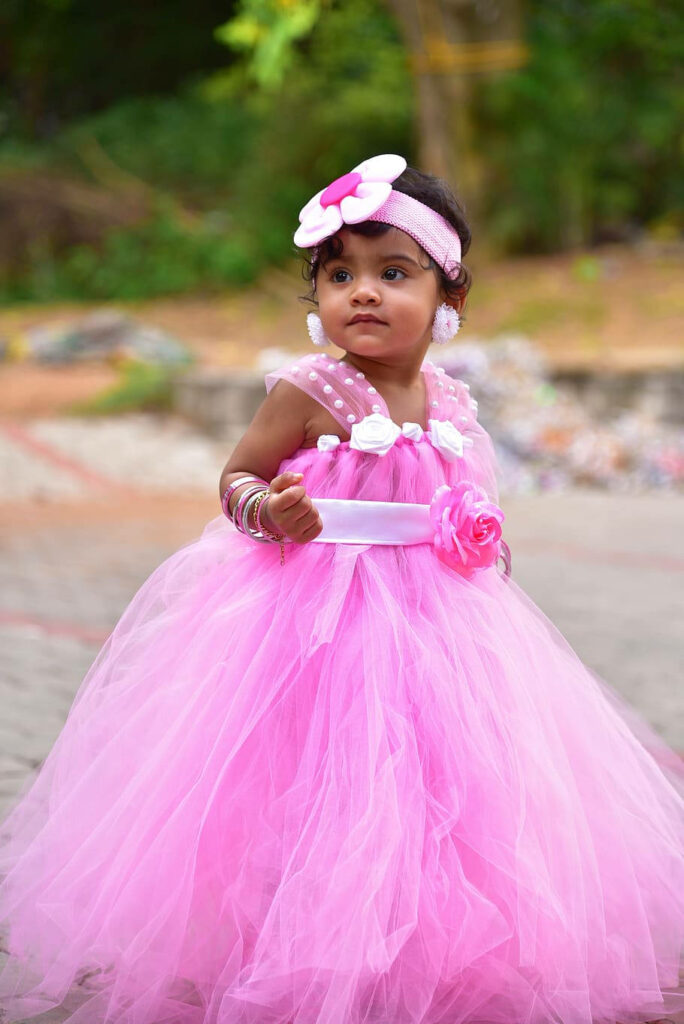 Adorable baby girl in fluffy pink dress outdoors radiating innocence and sweetness wallpaper