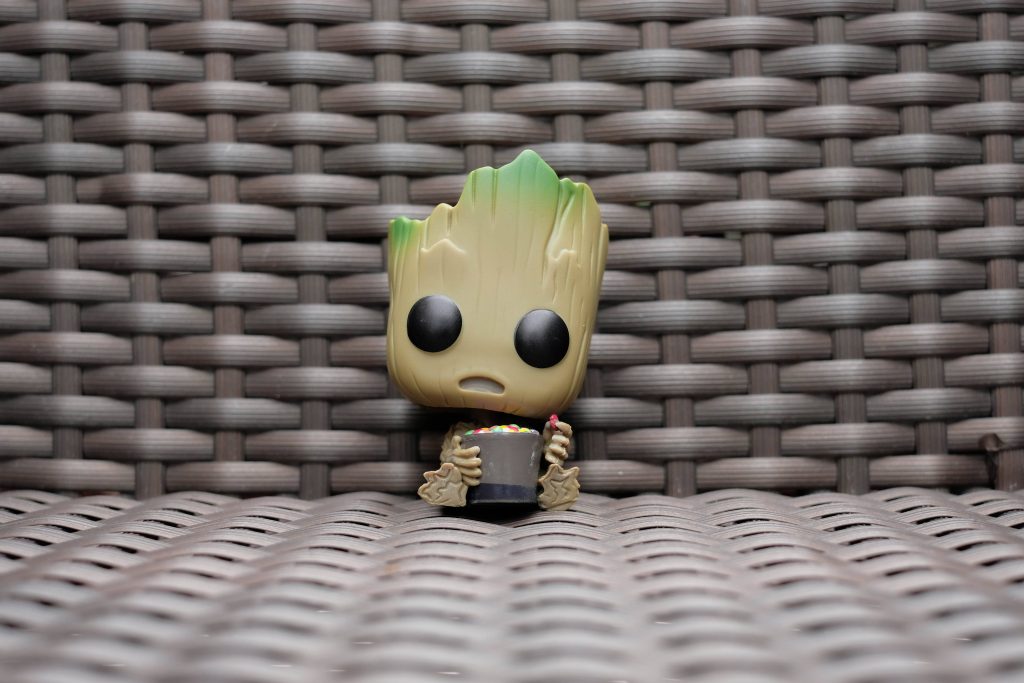 Close-up Baby Groot Funko Pop holding treats on brown wicker texture Marvel toy wallpaper