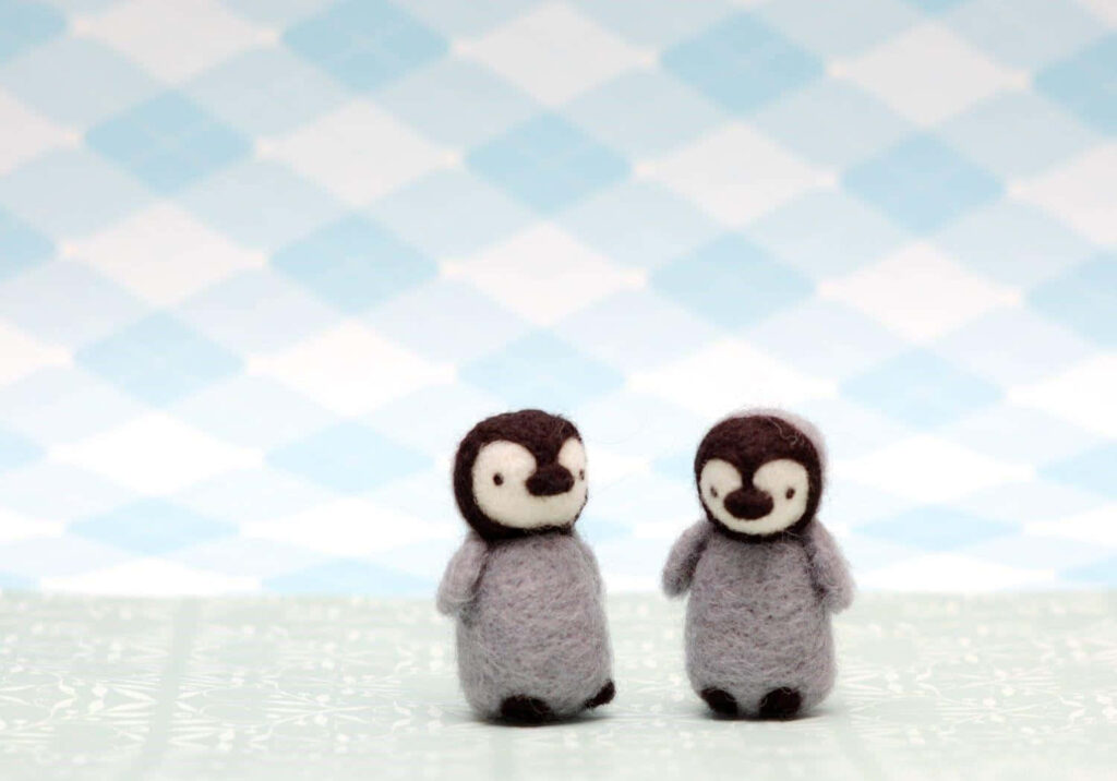 Adorable Felted Baby Penguins on Pastel Checkered Wallpaper Background