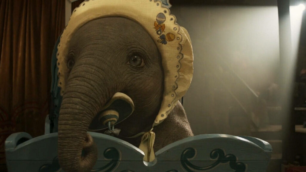 Adorable baby Dumbo with big eyes wearing bonnet holding pacifier on warm circus wallpaper background