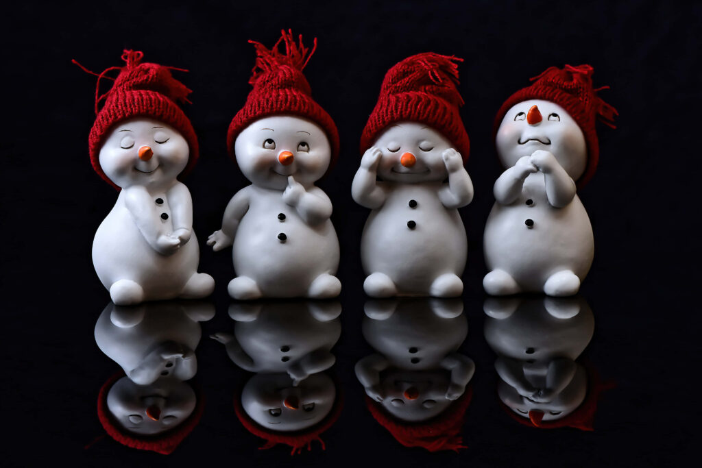 Festive Snowmen Figurines with Red Hats on Black Wallpaper Background