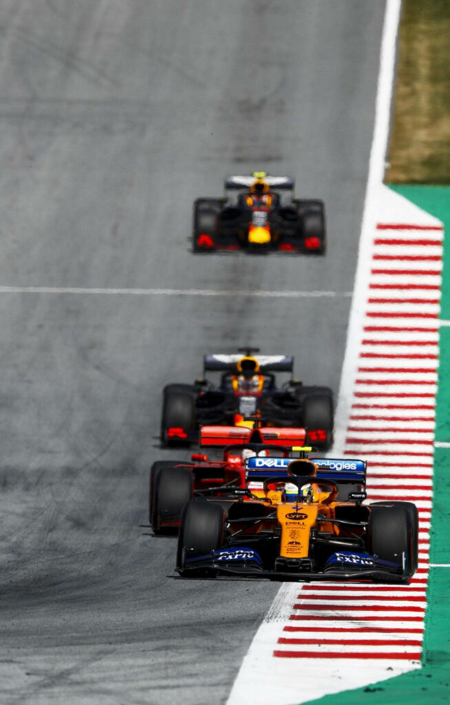 F1 race car speeding on track with two rival cars close behind intense Formula 1 action wallpaper