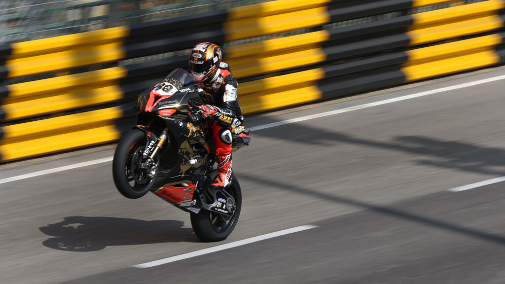 Thrilling Motorcyclist Wheelie Wallpaper: Power & Precision Action