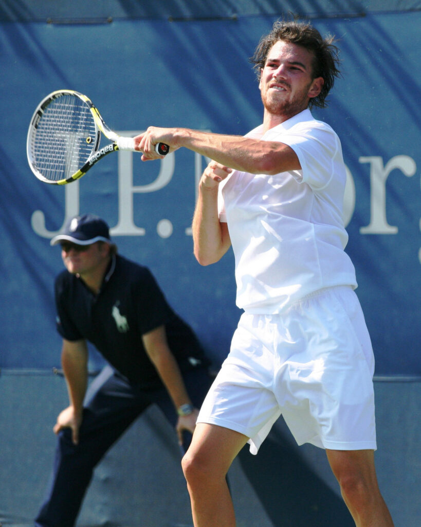 Adrian Mannarino hitting a powerful backhand in intense tennis match showcasing athletic skill Wallpaper