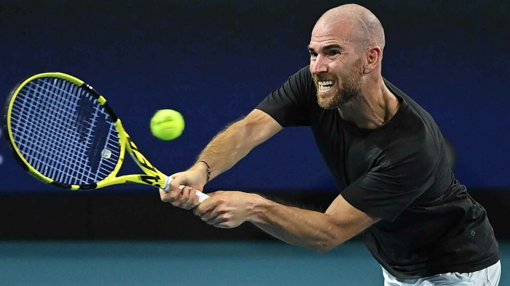 Adrian Mannarino intensely hitting tennis ball with racket in dynamic sports wallpaper background