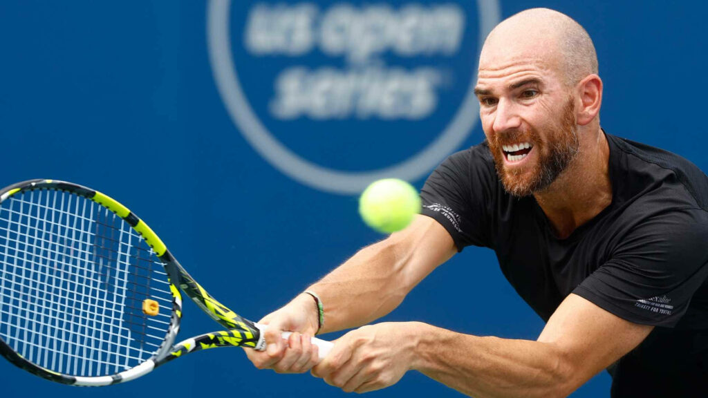 Adrian Mannarino hitting tennis ball with racket intense focus blue court background wallpaper